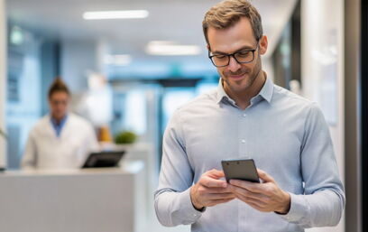 Mann nutzt die Co-med App auf dem Smartphone zur Bestellung von Praxisbedarf, Arzt im Hintergrund