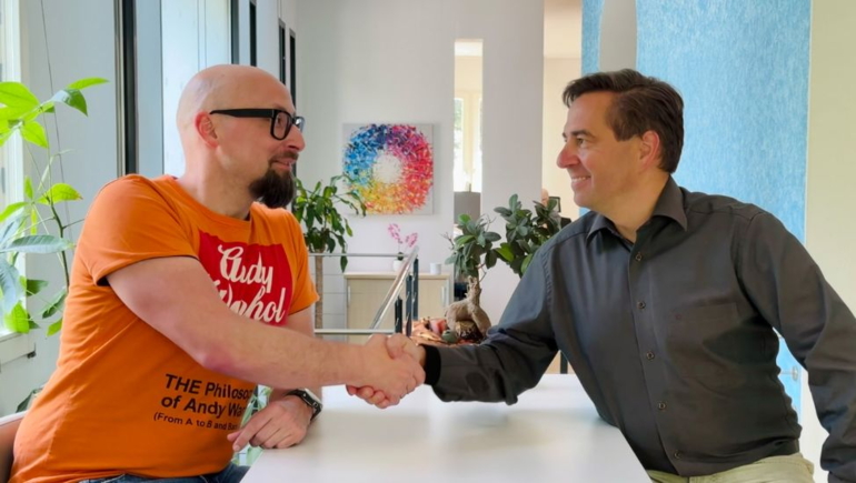 Ronny Büchner und Tino Favetto sitzen sich gegenüber und reichen sich die Hände zum Handschlag.