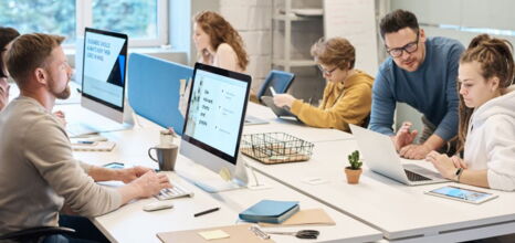Team arbeitet an Computern und Tablets in einem modernen Büro