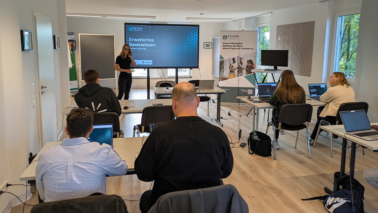 ESYON Schulung mit Vortragender vor Bildschirm und Teilnehmenden mit Laptops
