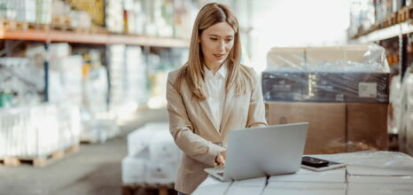 Frau arbeitet in Lagerhalle mit einem Laptop