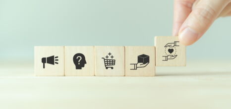 Hand ordnet Holzklötze mit Symbolen für Marketing, E-Commerce und Kundenservice