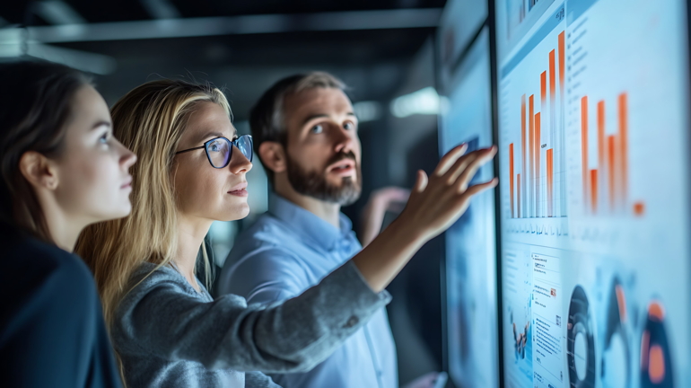 Team analysiert Daten auf großem Bildschirm für optimiertes Monitoring mit Microsoft Dynamics 365