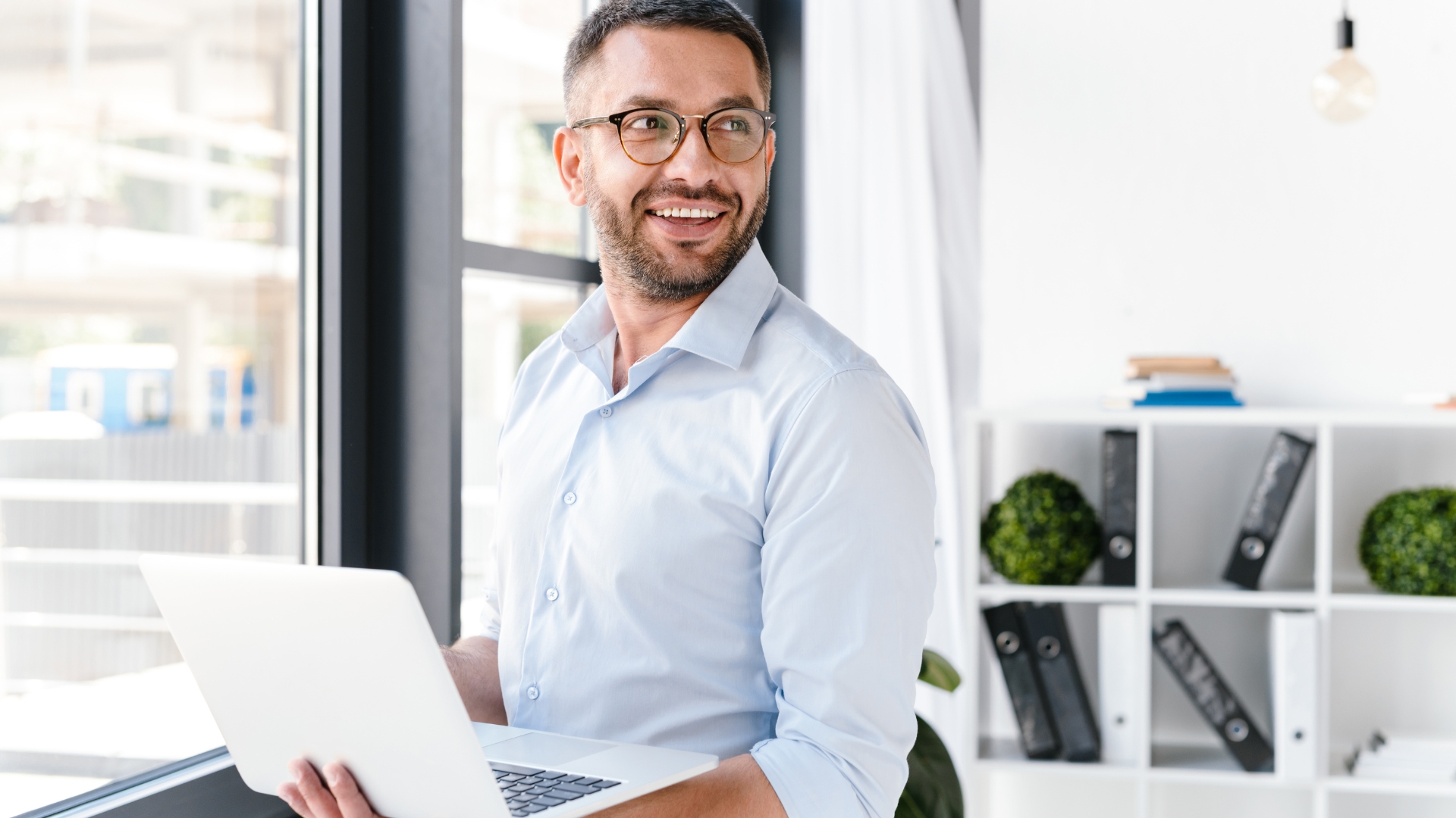 Mann im Büro mit Laptop in der Hand